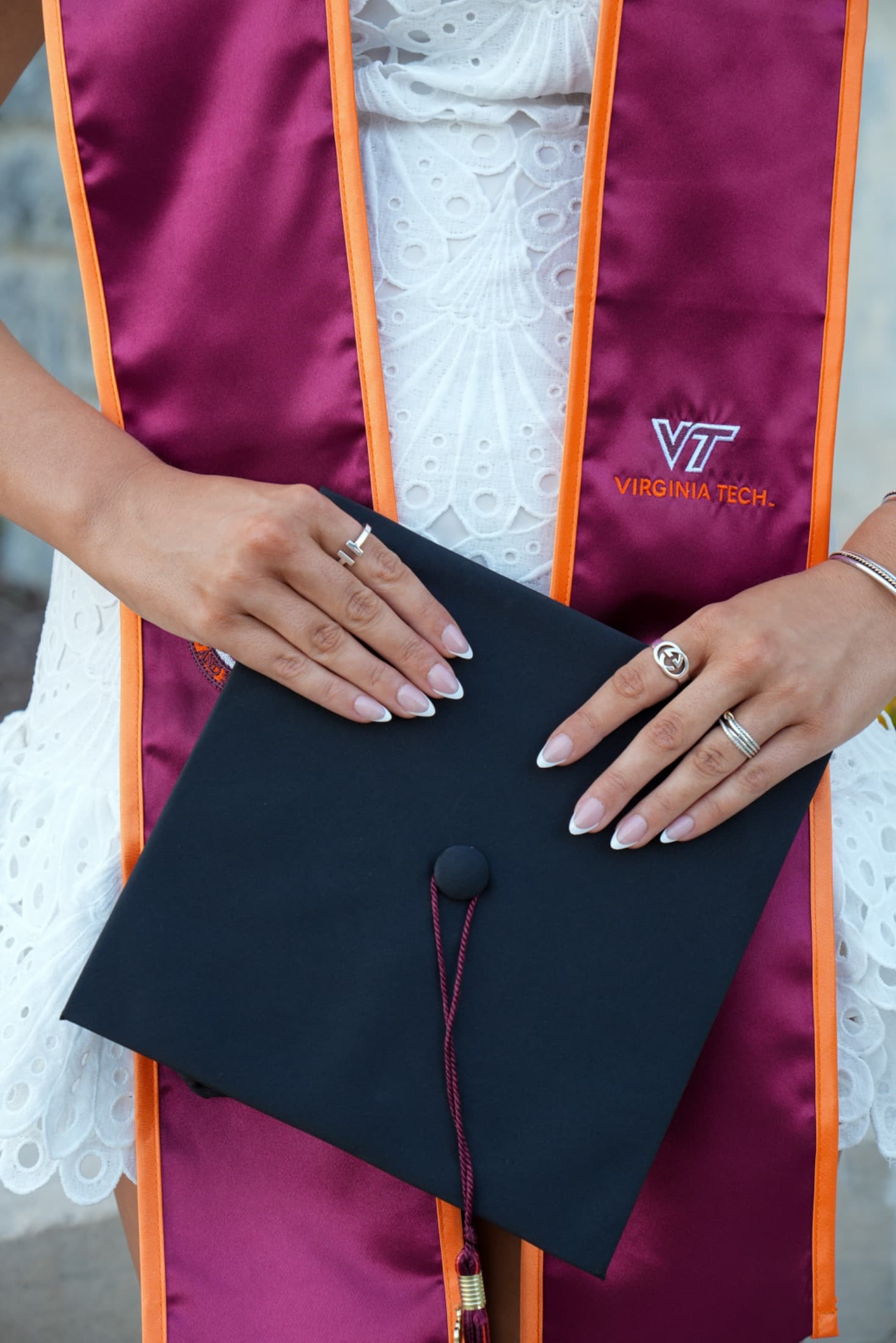 A senior in her stole standing at midfield beneath the Hokies jumbotron