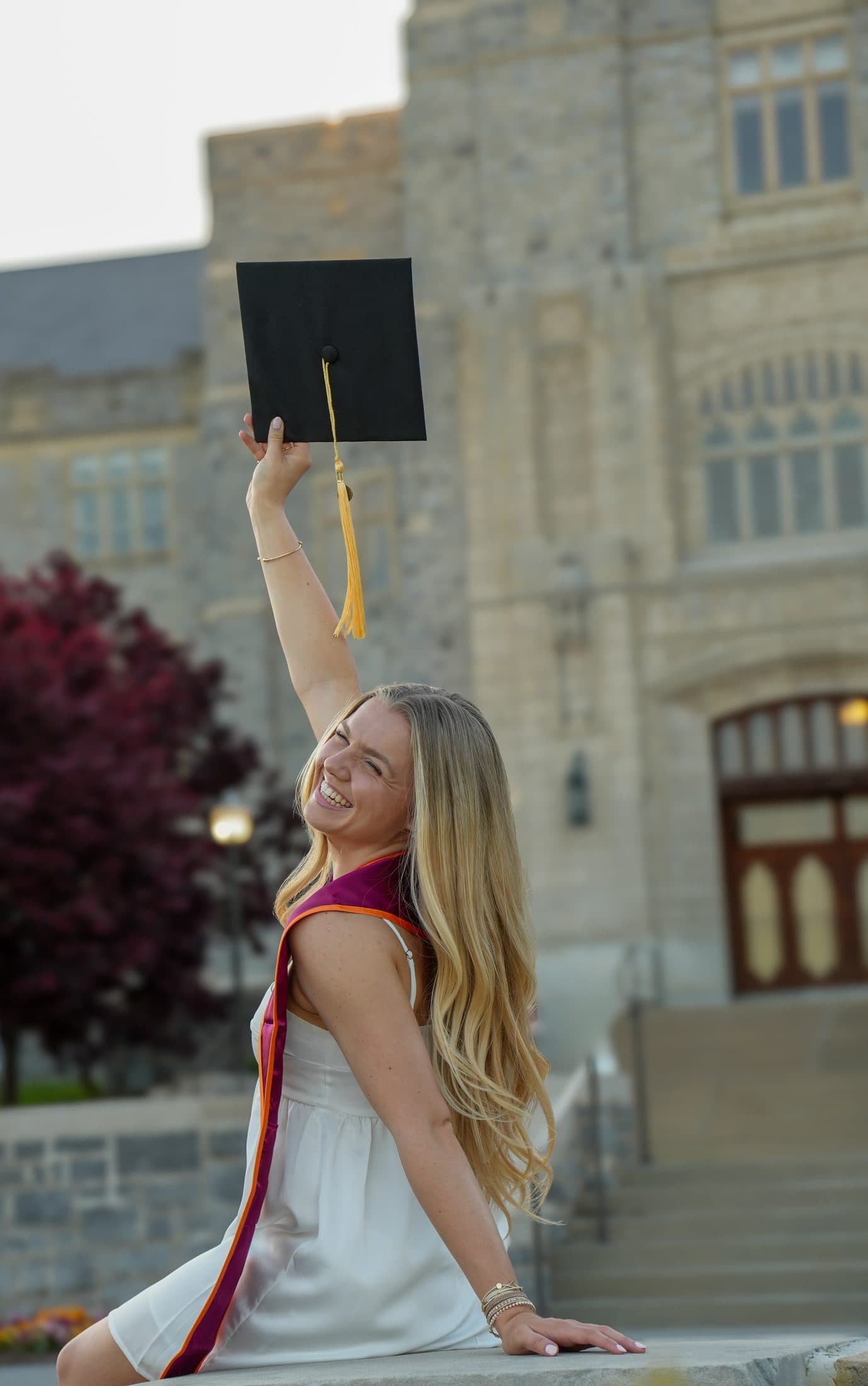 A graduate beneath grand arched wooden doors in her gown
