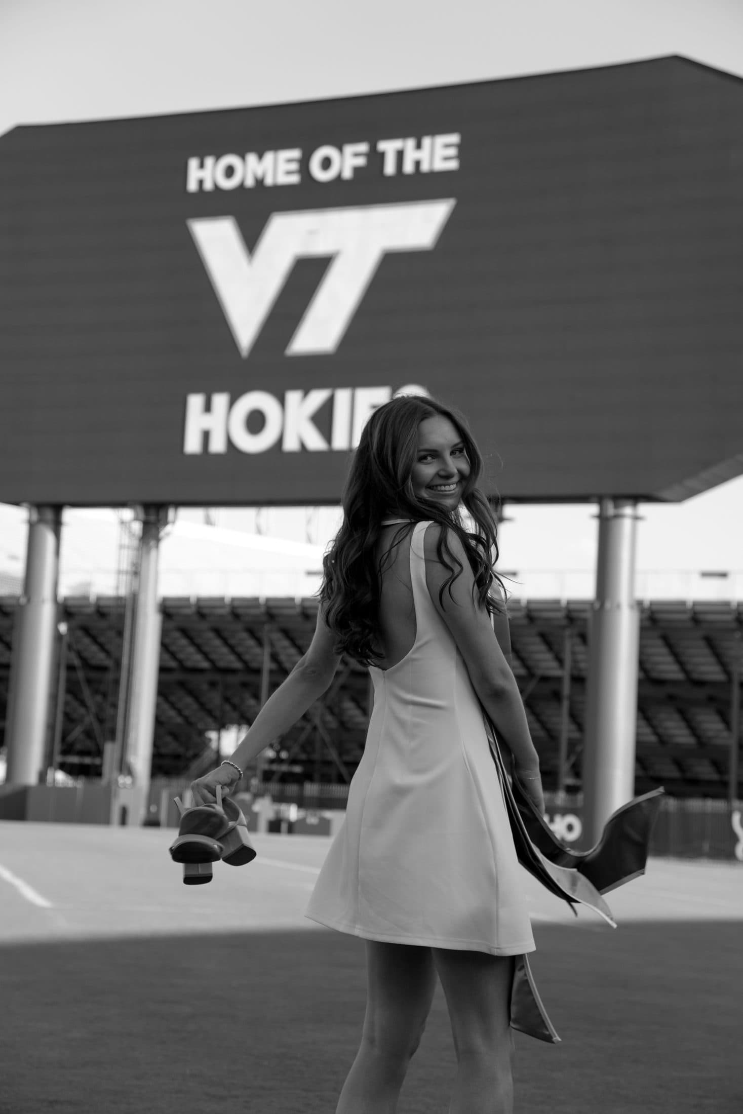 A senior alone on the field beneath the glowing jumbotron in black and white