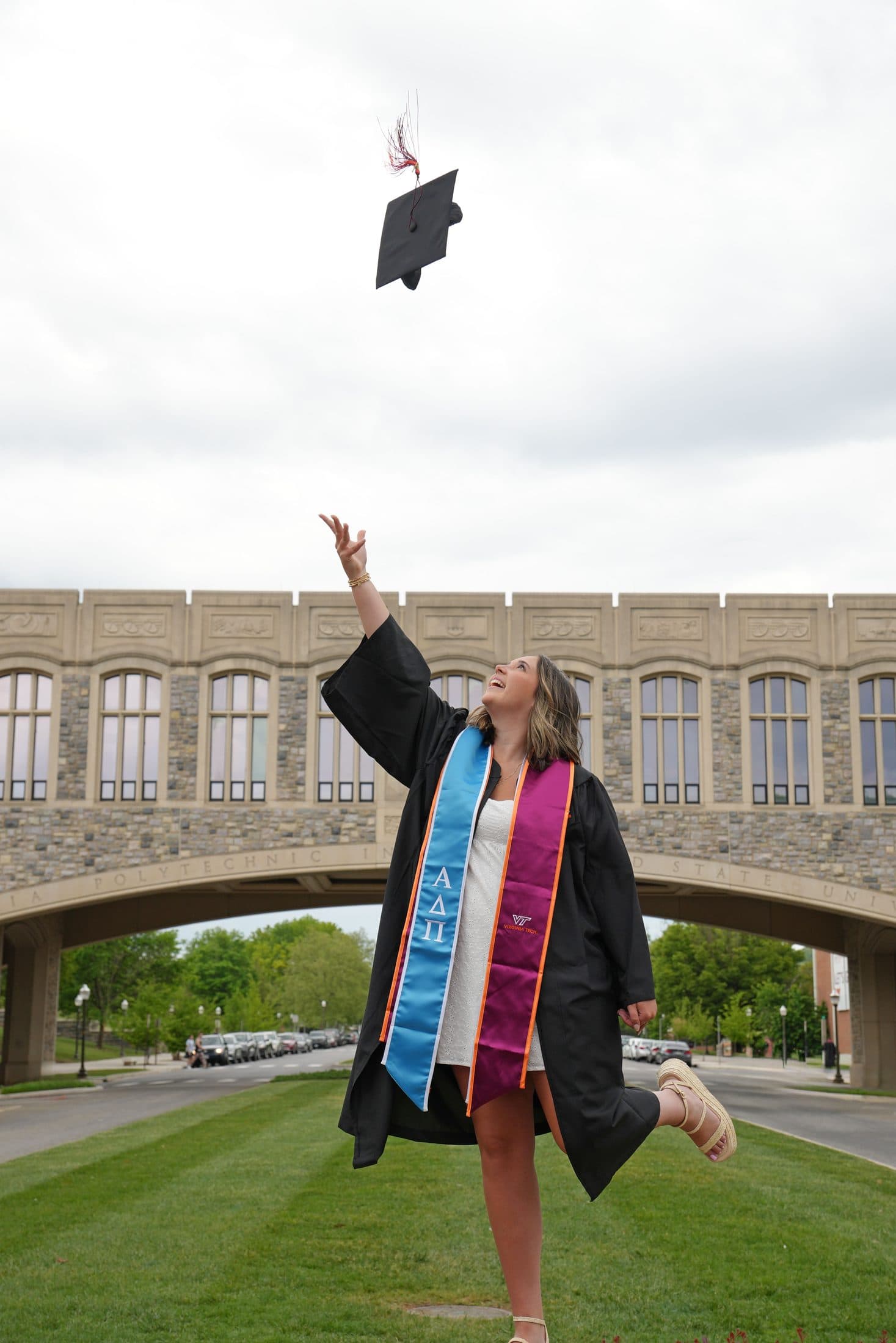 A graduation cap tossed against open sky beneath a stone archway