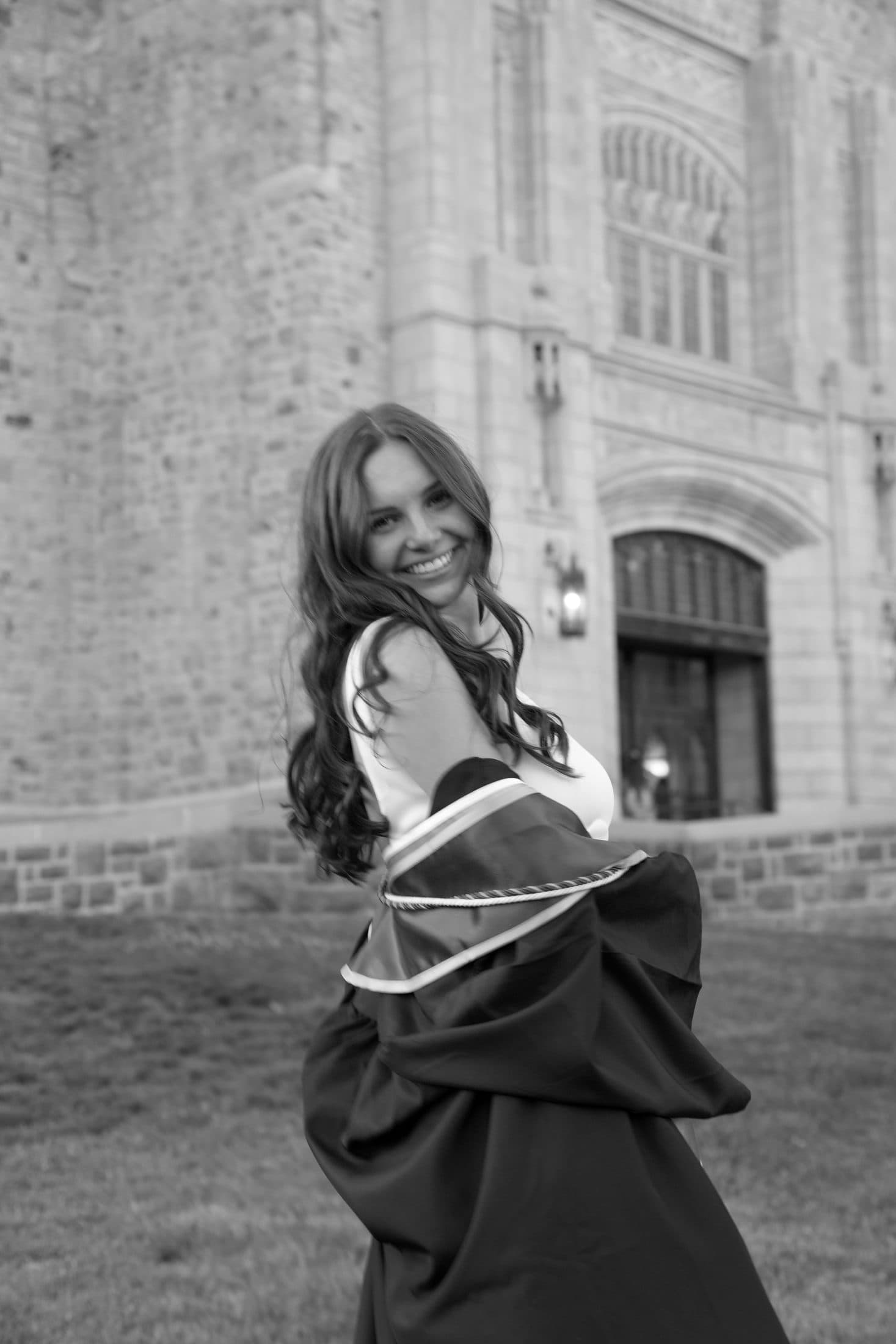 A senior raising a champagne bottle on the steps of Burruss Hall