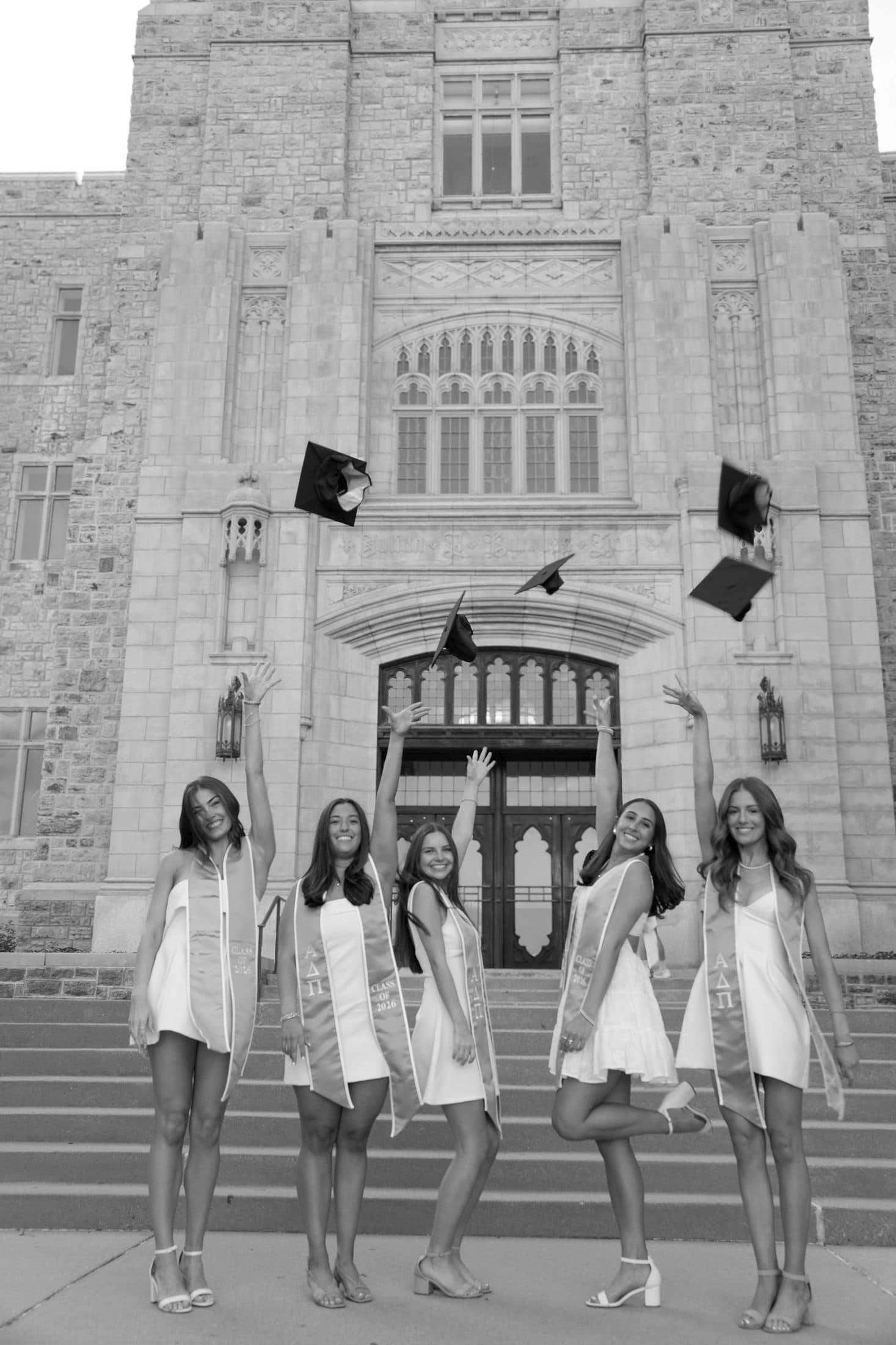 Five seniors flinging their caps into the air on the Burruss steps