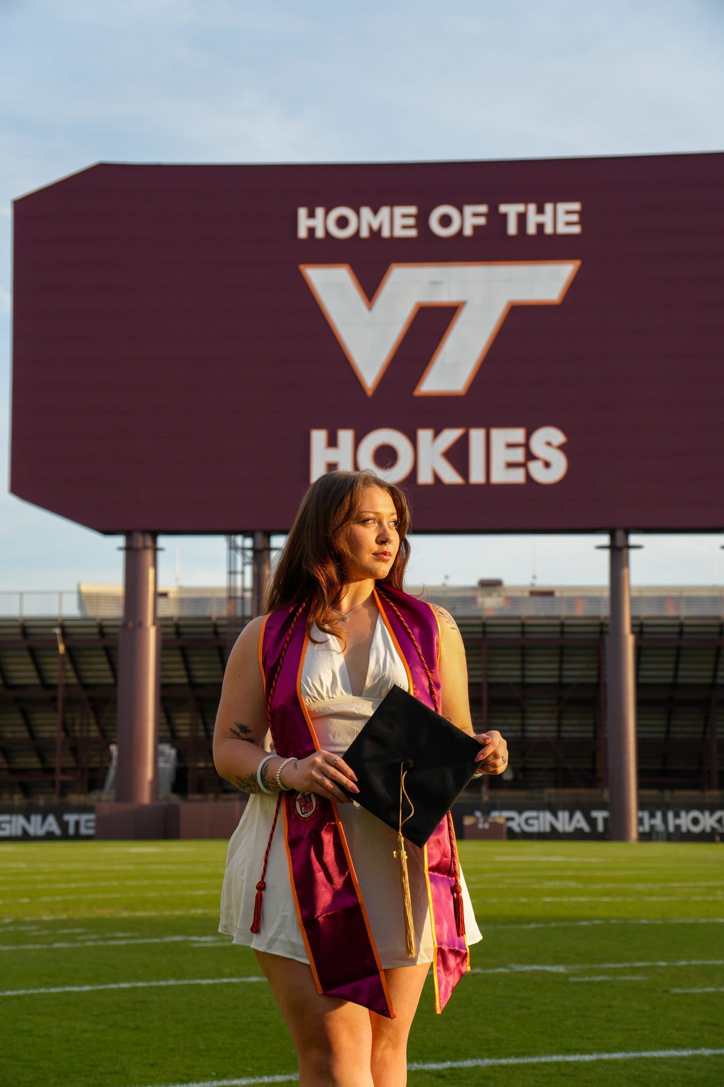 A senior in her stole standing at midfield beneath the Hokies jumbotron