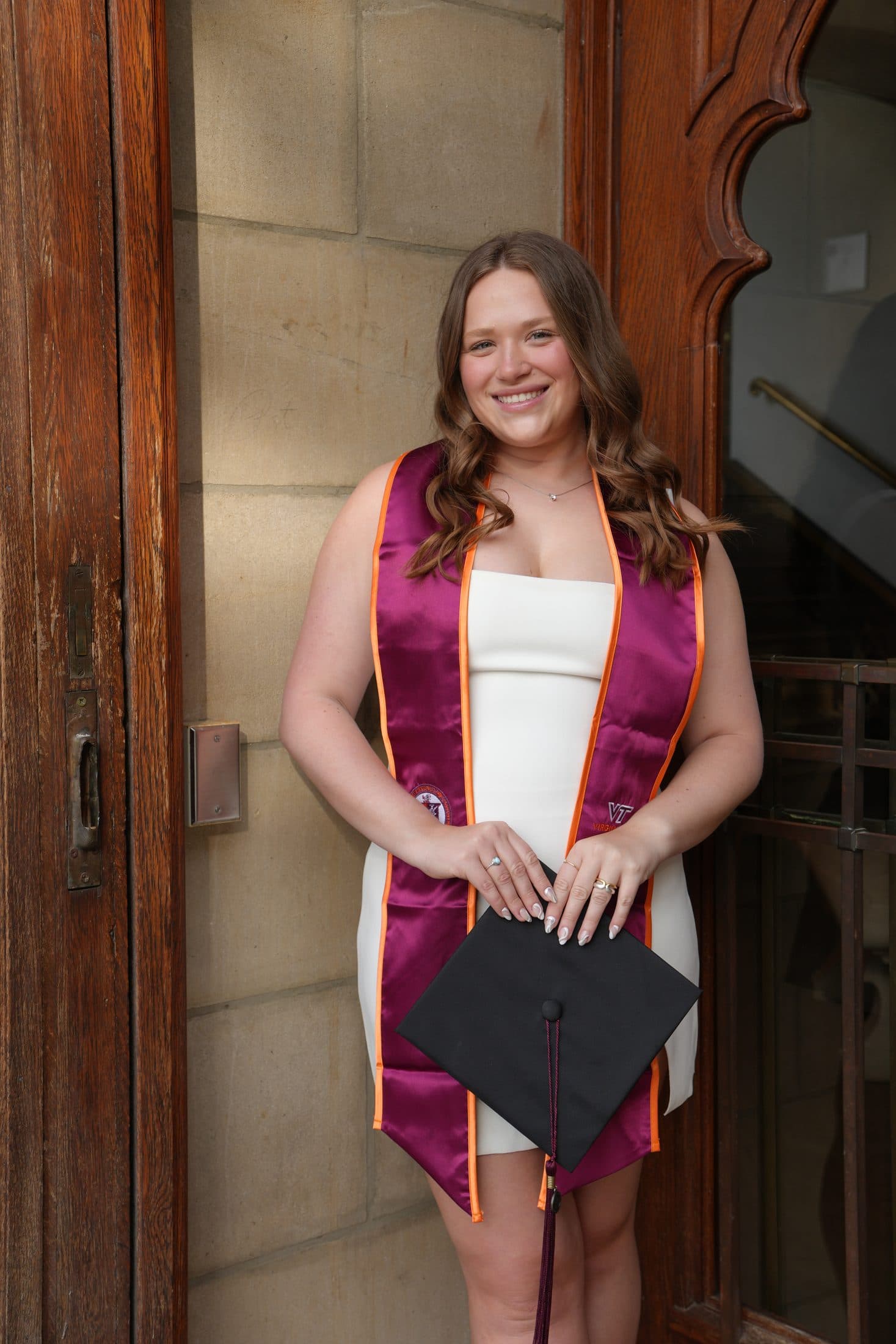 A senior cradling her cap in a warm stone doorway