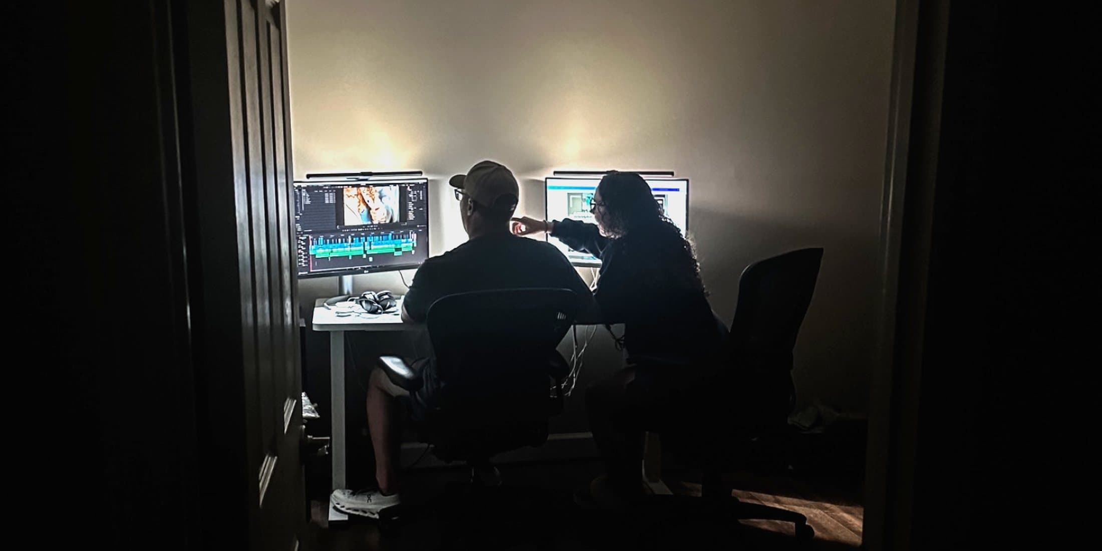 Taylor and Joe at work in the edit bay, lit only by the monitors
